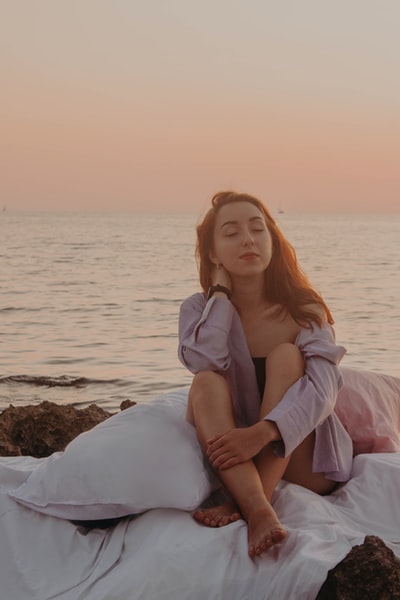 一个穿着紫色长袍的女人坐在一个白色的枕头旁，横过水面